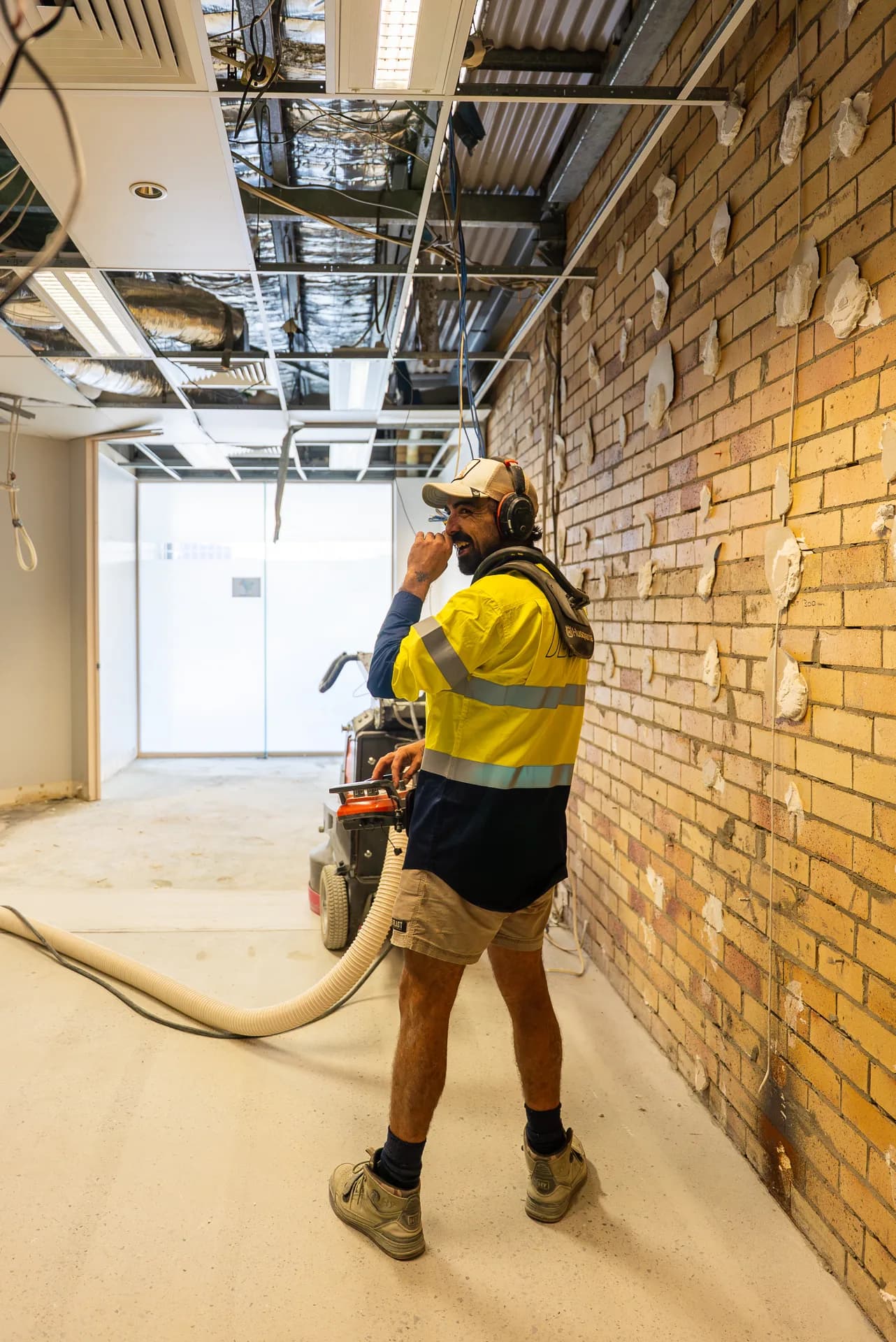 ICGC operator with hearing protection walking through a dust-free commercial grinding site with Husqvarna equipment